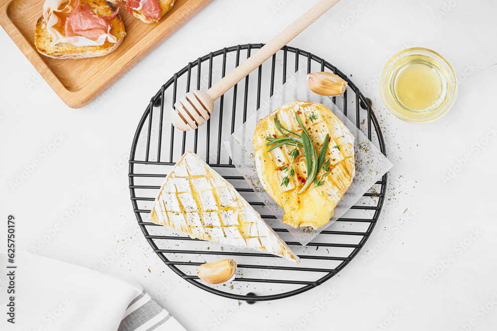 Grid with tasty baked Camembert cheese on grey background