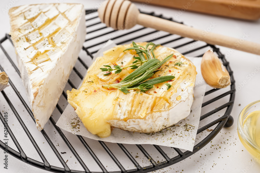 Grid with tasty baked Camembert cheese on grey background