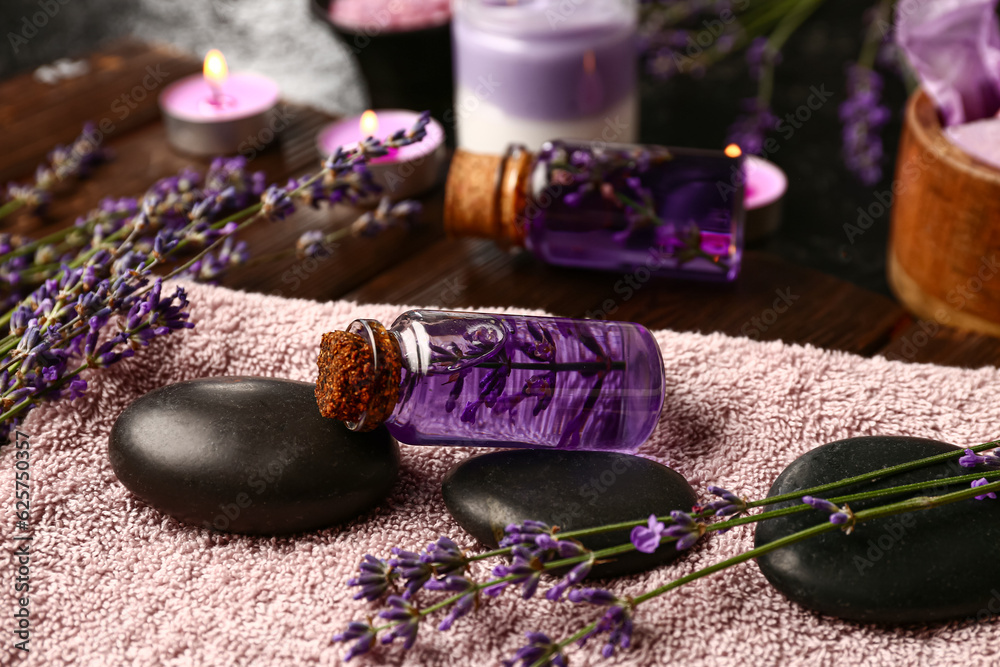 Composition with bottles of essential oil, spa accessories and lavender flowers on wooden table, clo