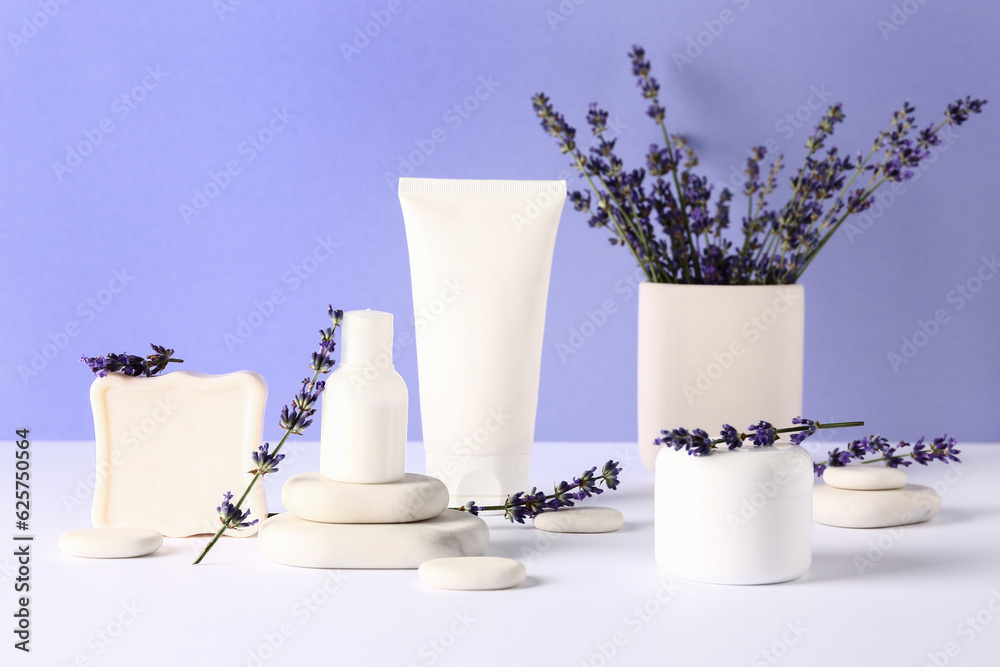 Composition with cosmetic products, spa stones and lavender flowers on light table against color bac