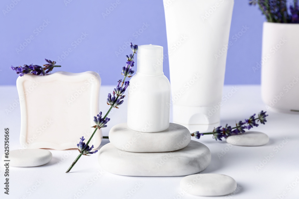 Composition with cosmetic products, spa stones and lavender flowers on light table against color bac