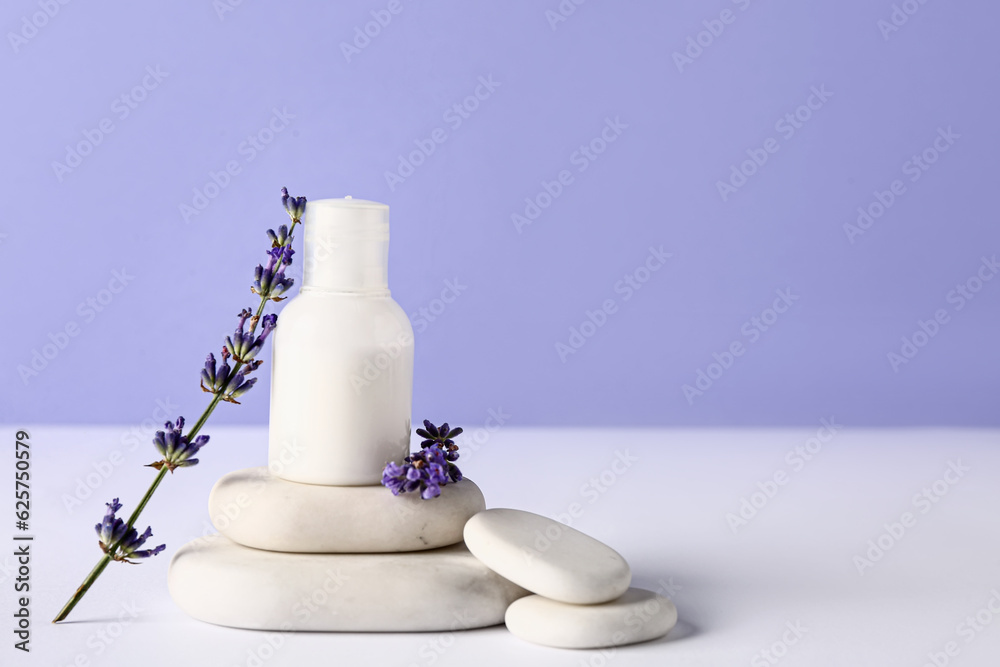 Composition with cosmetic product, spa stones and lavender flowers on light table against color back