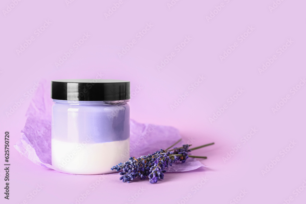 Jar of cosmetic product and lavender flowers on lilac background