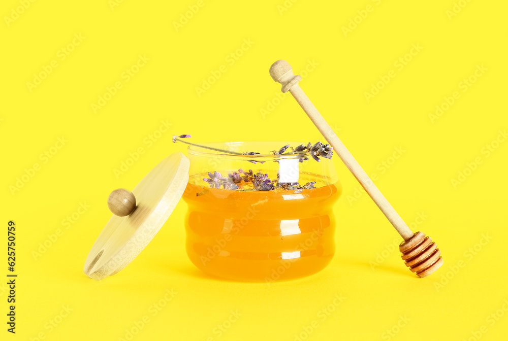 Jar of sweet lavender honey, dipper and flowers on yellow background