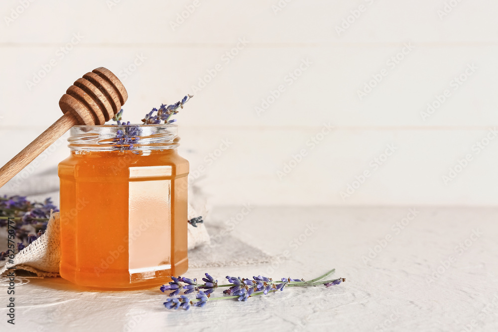 Jar of sweet lavender honey, dipper and flowers on white background