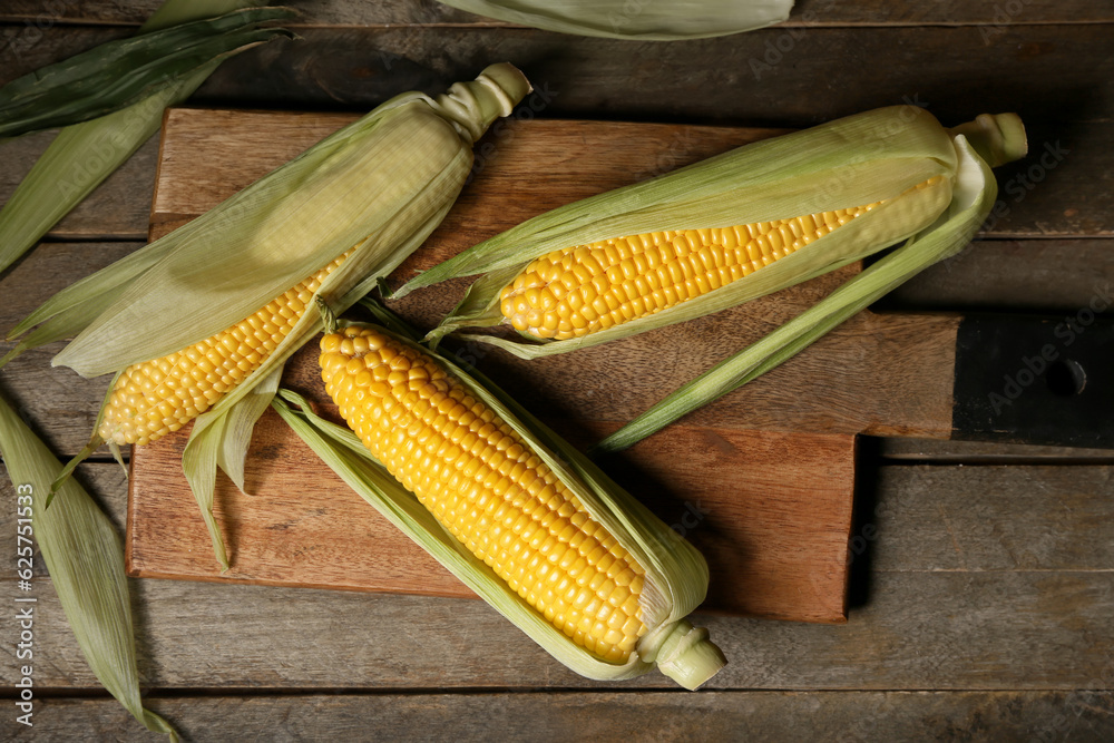 Board with fresh corn cobs on wooden table