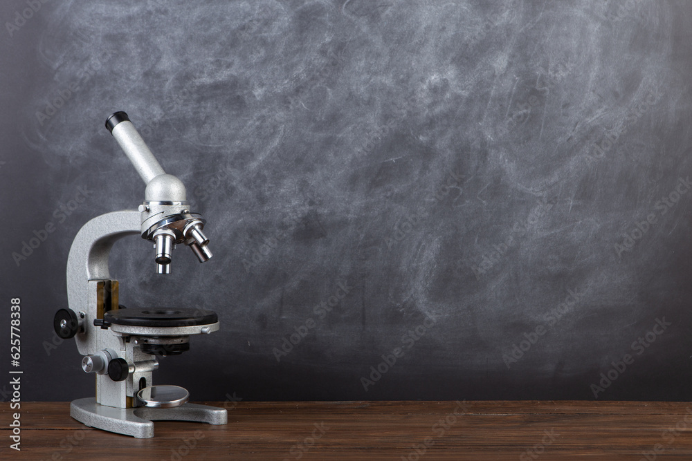 Back to school - microscope on the desk, Education concept. Blackboard background