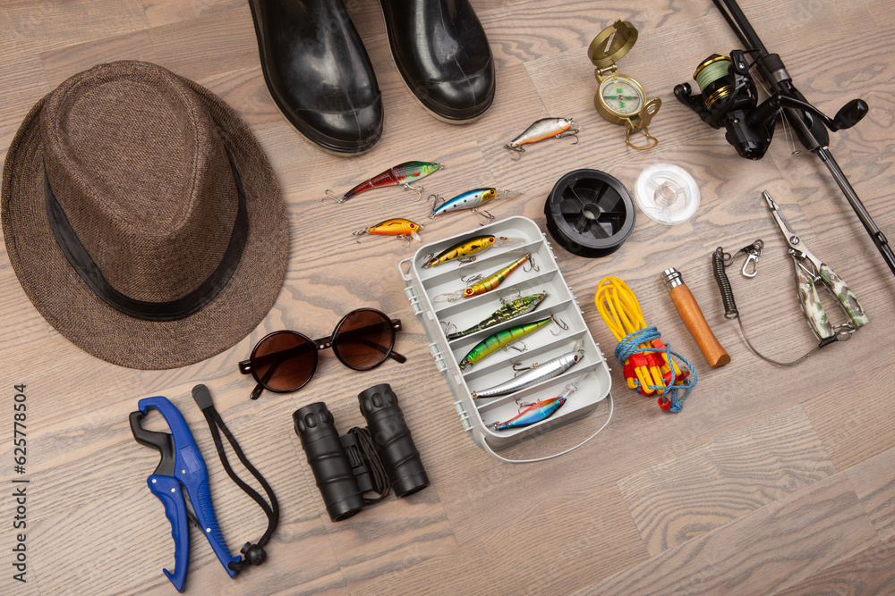 Fishing rod, tackles and other stuff for recreation activity on the wooden desk. Fishing season conc