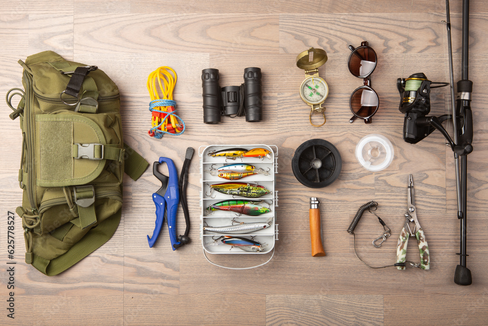 Fishing rod, tackles and other stuff for recreation activity on the wooden desk. Fishing season conc