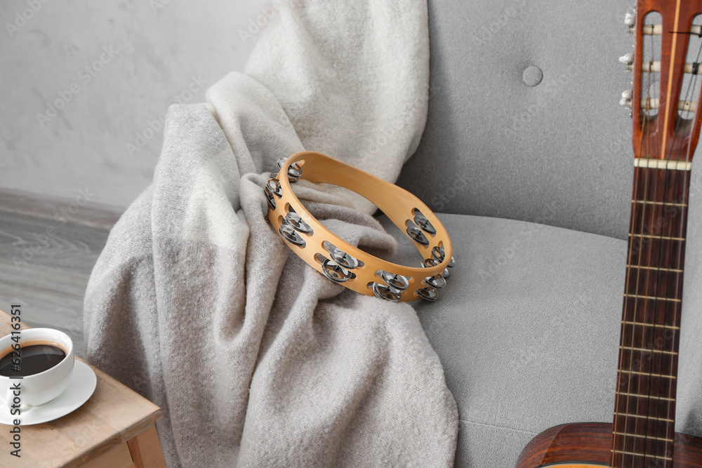 Tambourine on armchair and guitar in room