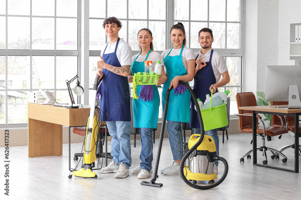 Young janitors with cleaning supplies in office