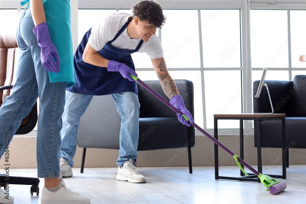 Male janitor mopping floor in office