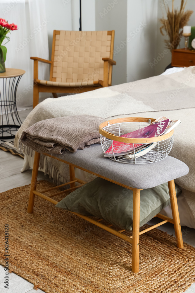 Bedside bench with pillow, blanket and magazines in bedroom