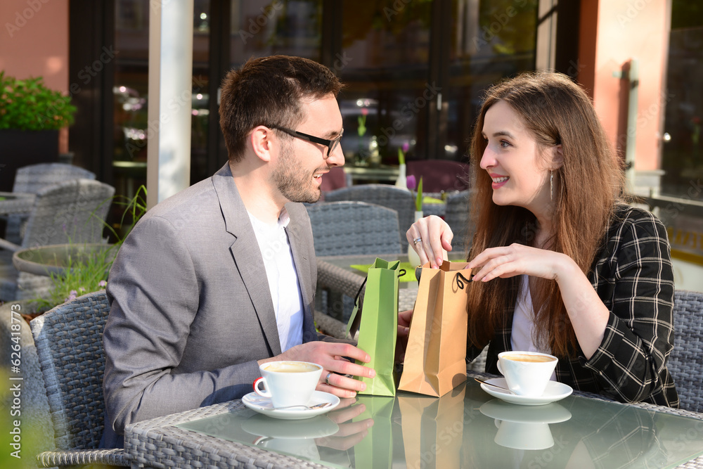 Young man giving present for his girlfriend in restaurant on sunny spring day