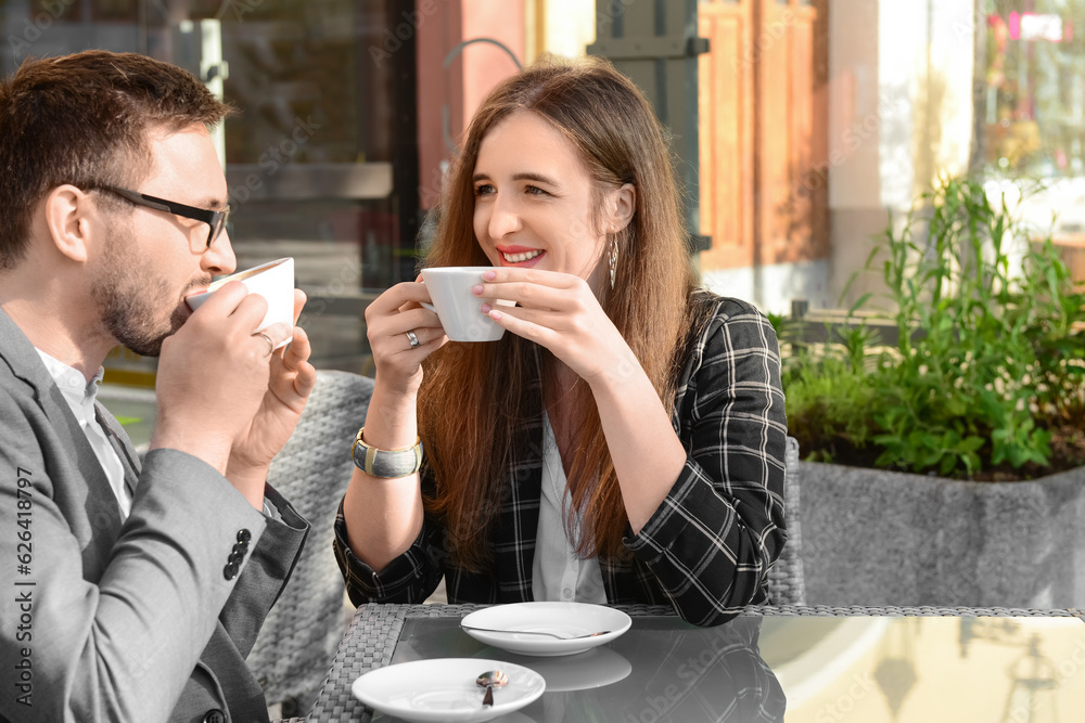 Beautiful happy loving couple sitting in restaurant and drinking coffee on sunny spring day