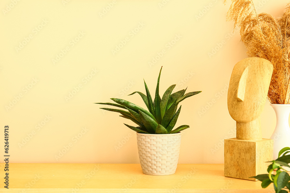 Green houseplant with decor on shelf near beige wall