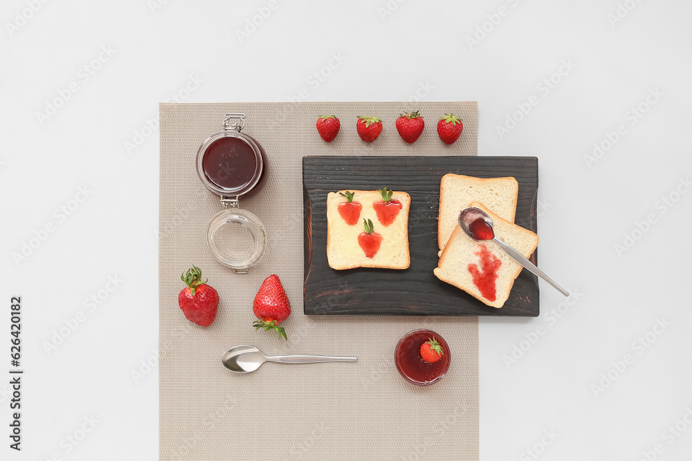 Board of tasty toasts with sweet strawberry jam on grey background