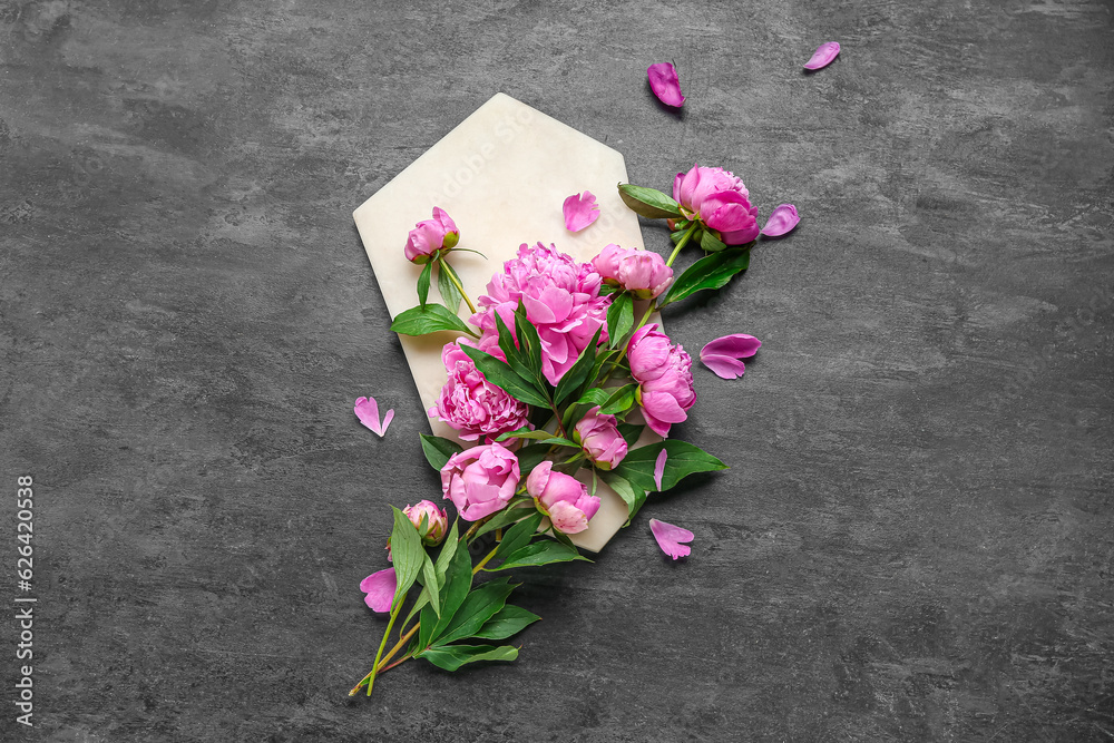 Composition with board and beautiful peony flowers on dark background