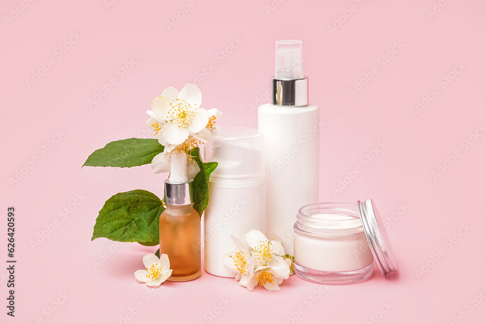 Set of cosmetic products and beautiful jasmine flowers on pink background