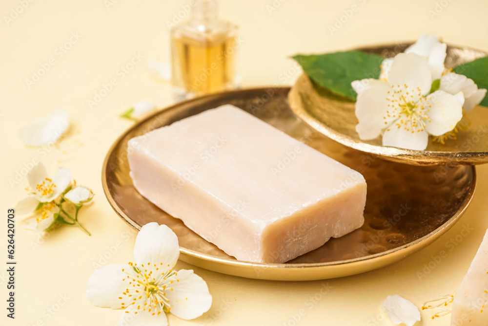 Plates with soap bar and beautiful jasmine flowers on color background, closeup