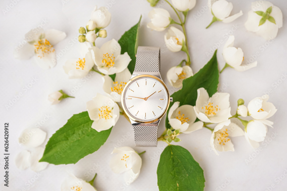 Composition with stylish wristwatch and beautiful jasmine flowers on light background