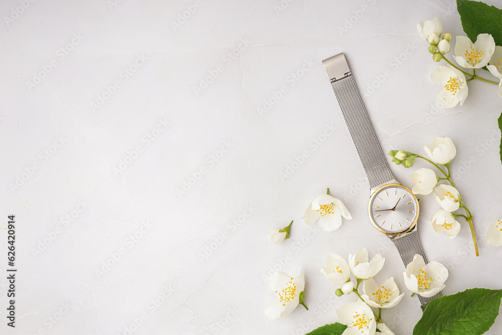 Composition with stylish wristwatch and beautiful jasmine flowers on light background