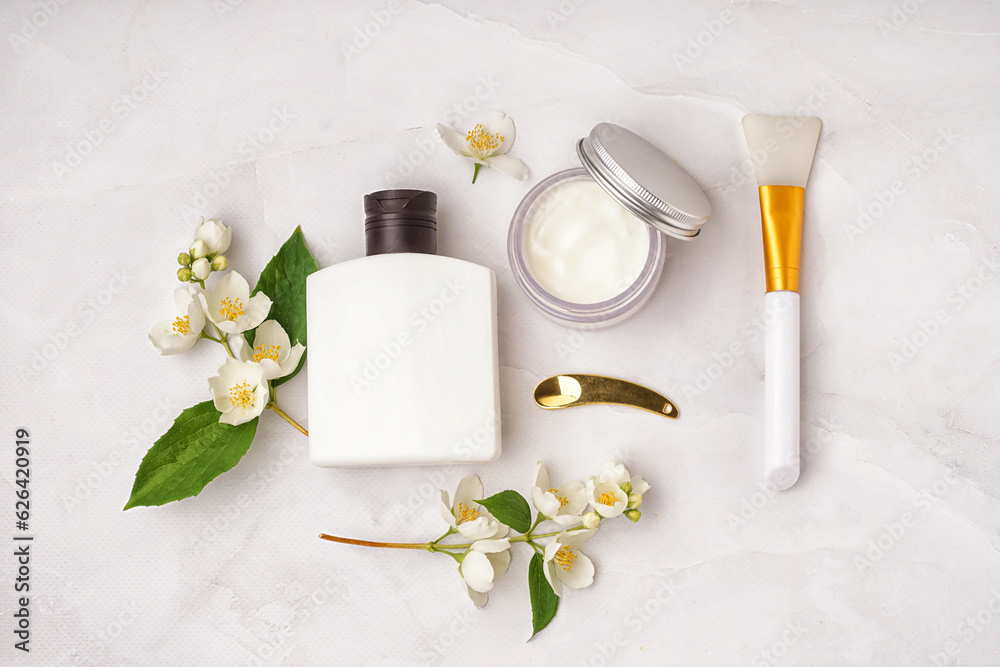 Composition with cosmetic products, spatulas and beautiful jasmine flowers on light background