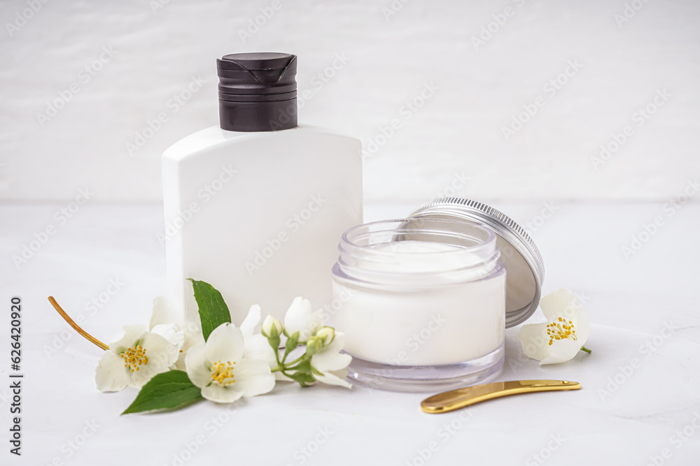 Cosmetic products and beautiful jasmine flowers on light background