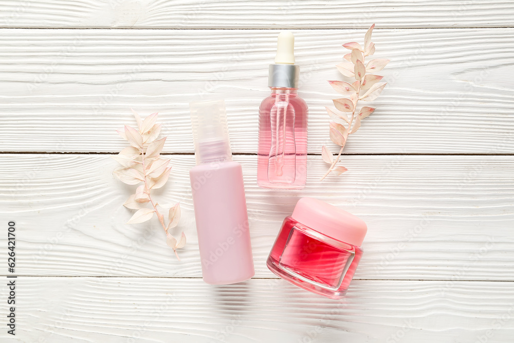 Composition with cosmetic products and dried plants on light wooden background