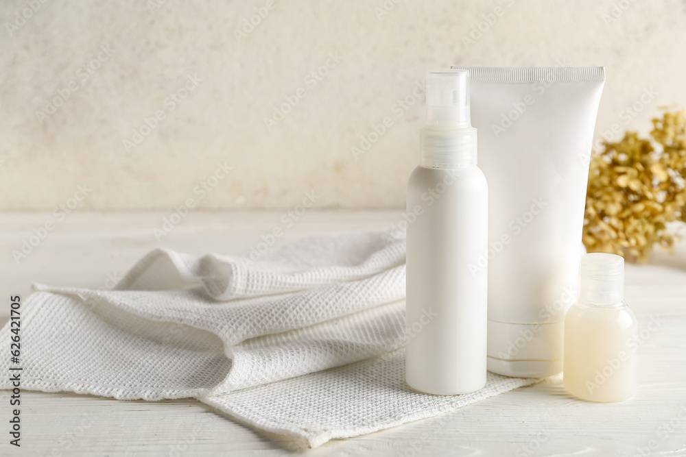 Set of cosmetic products and clean towel on light background