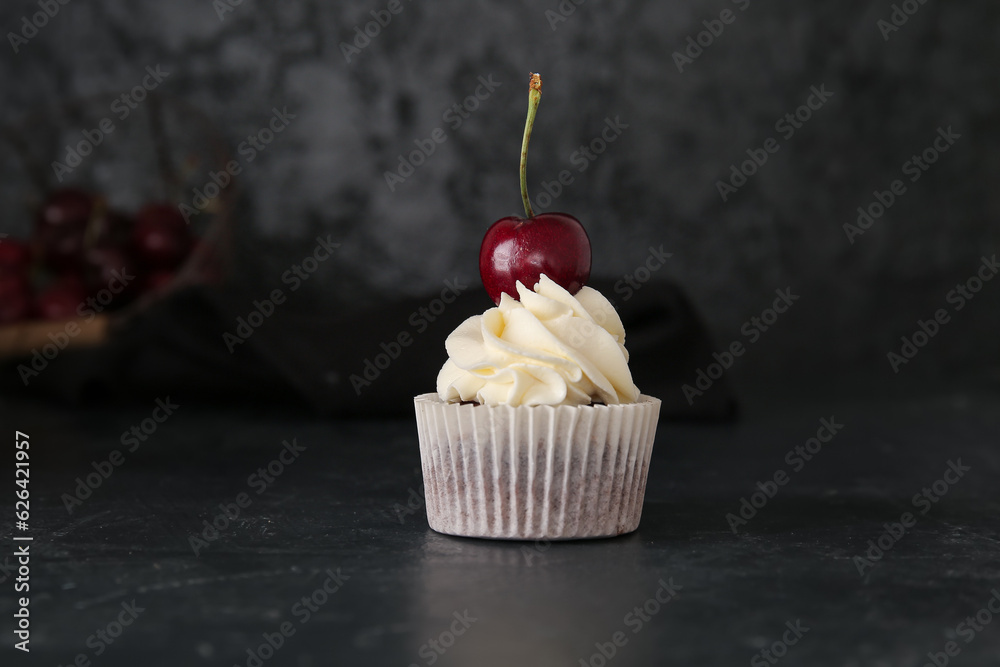 Tasty cherry cupcake on black background