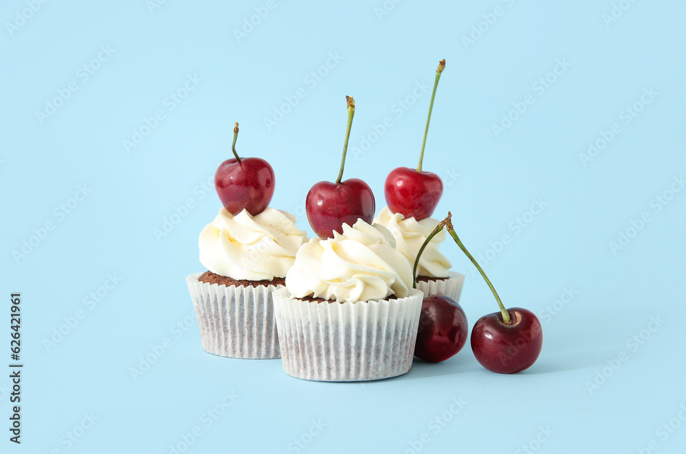 Tasty cherry cupcakes on blue background