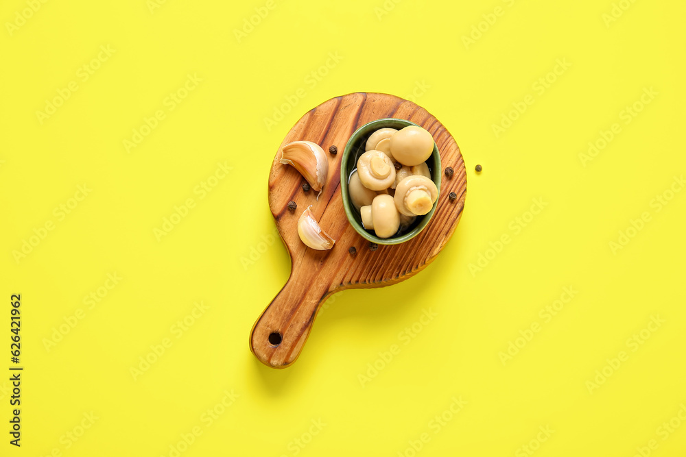 Bowl with canned mushrooms on yellow background