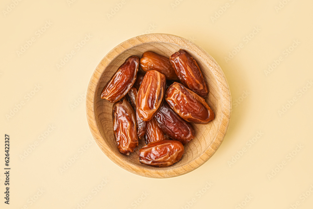 Bowl with dried dates on yellow background