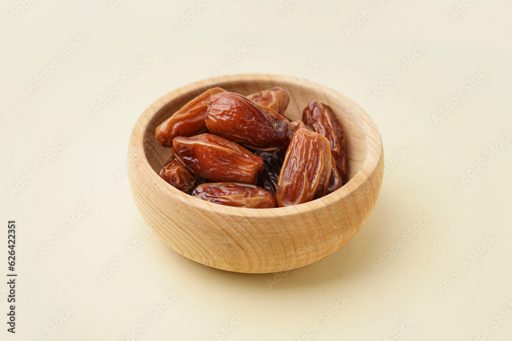 Bowl with dried dates on yellow background