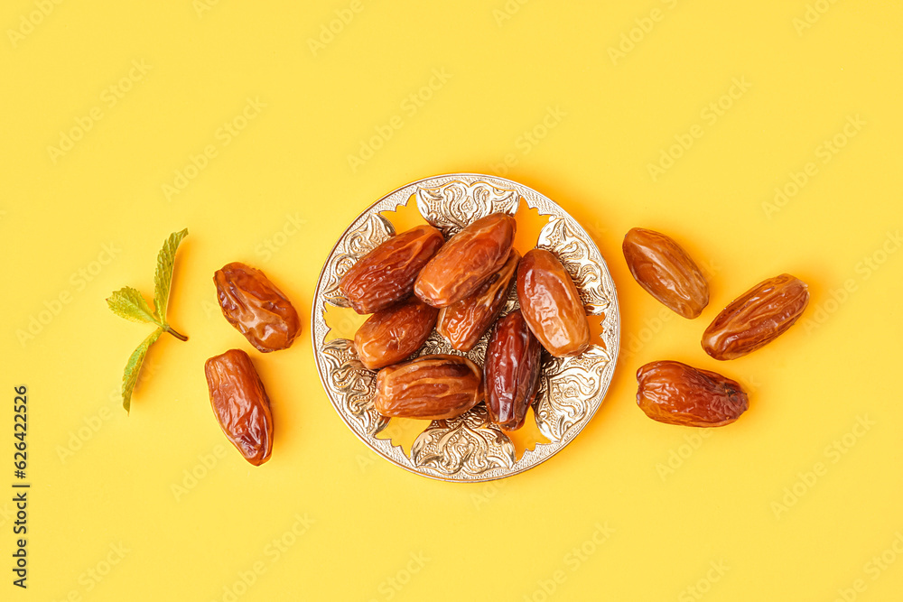 Bowl with dried dates on yellow background