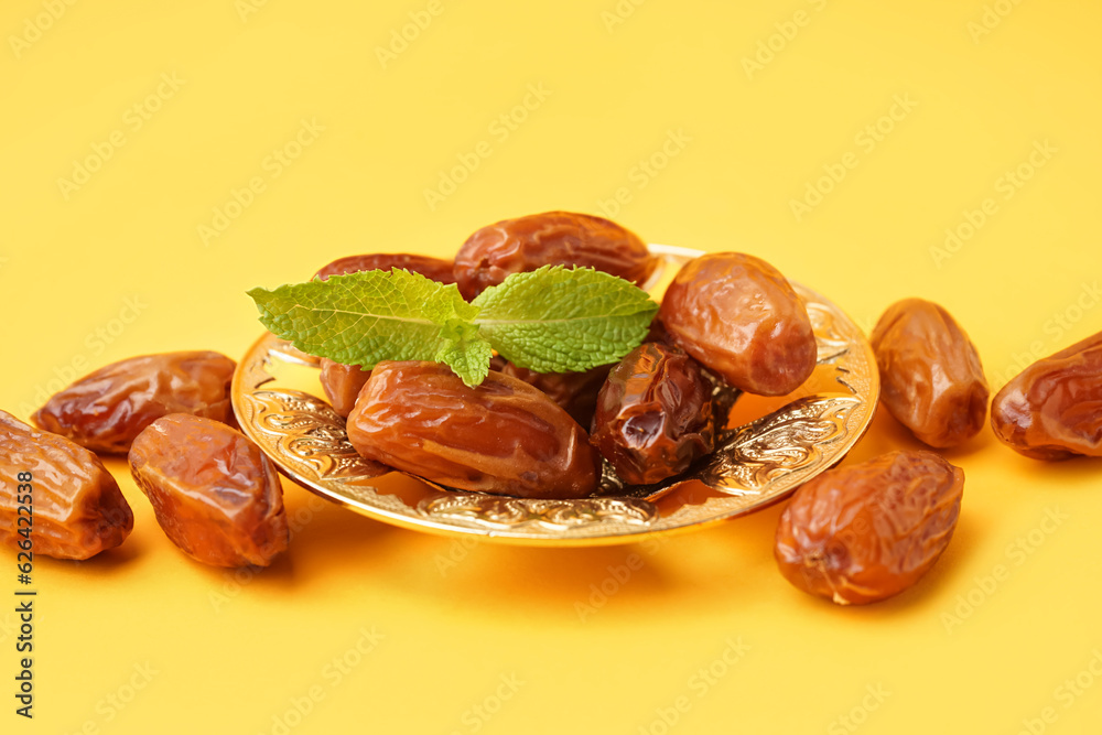 Bowl with dried dates on yellow background