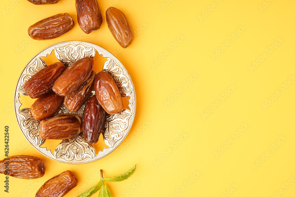 Bowl with dried dates on yellow background