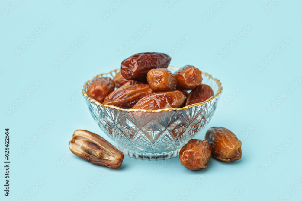 Bowl with dried dates on blue background