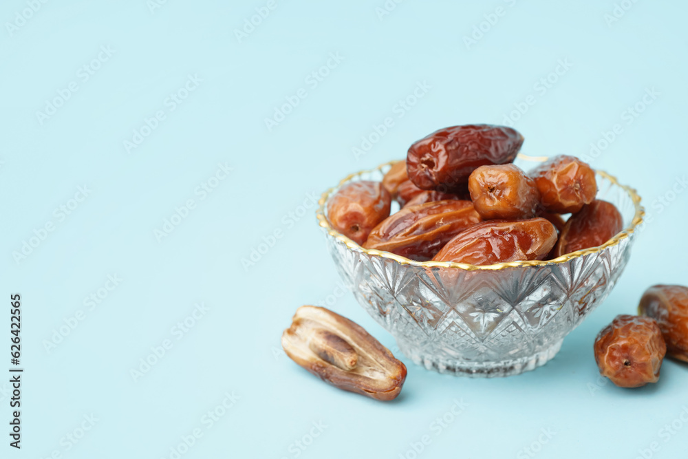 Bowl with dried dates on blue background