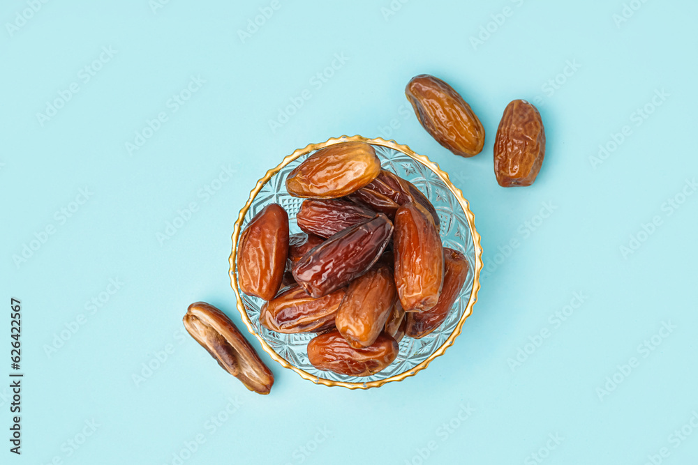 Bowl with dried dates on blue background