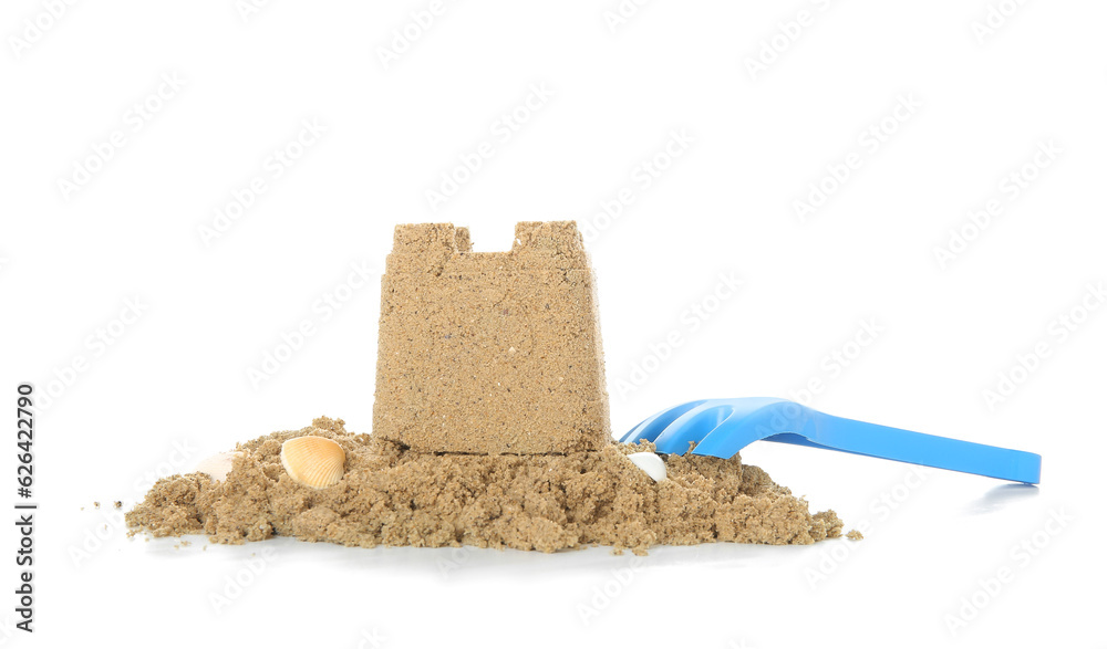 Castle made of sand with toy rake isolated on white background