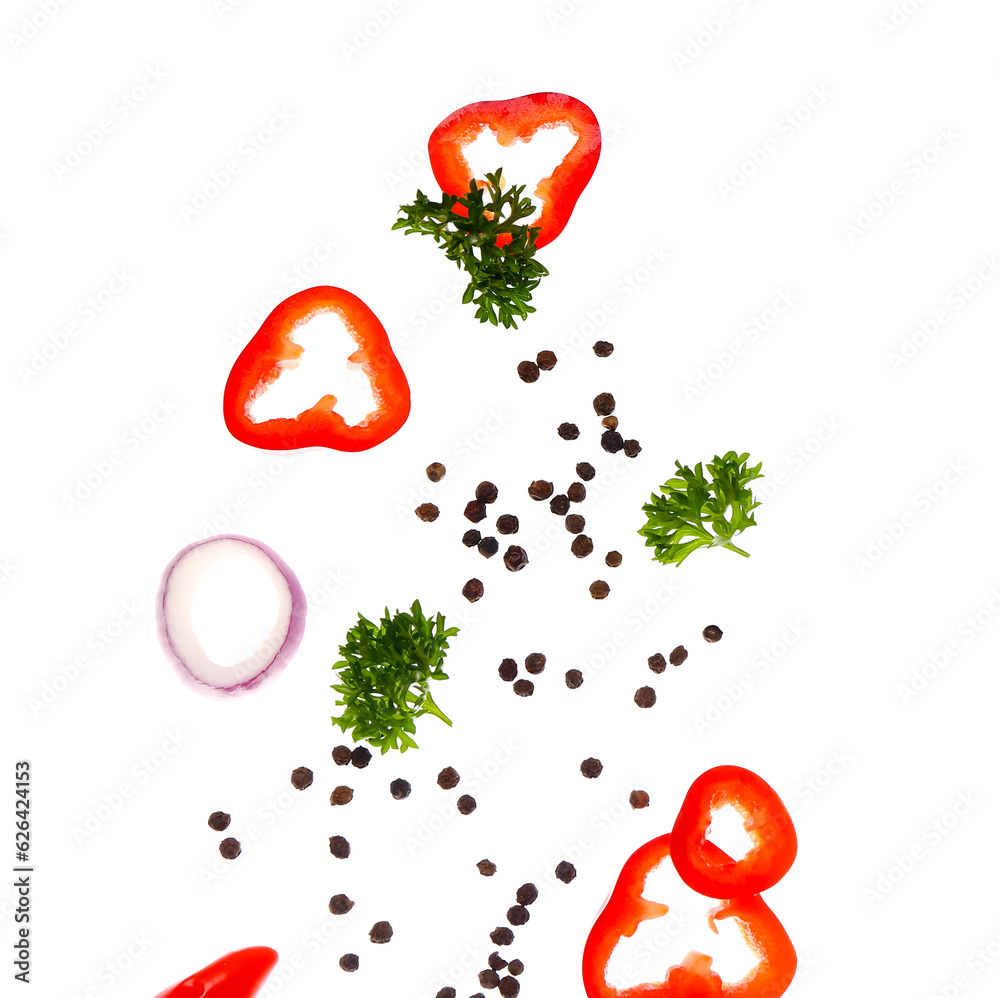 Flying peppercorns, chili pepper, parsley and onion on white background