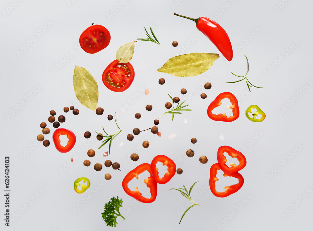 Flying spices and vegetables on grey background