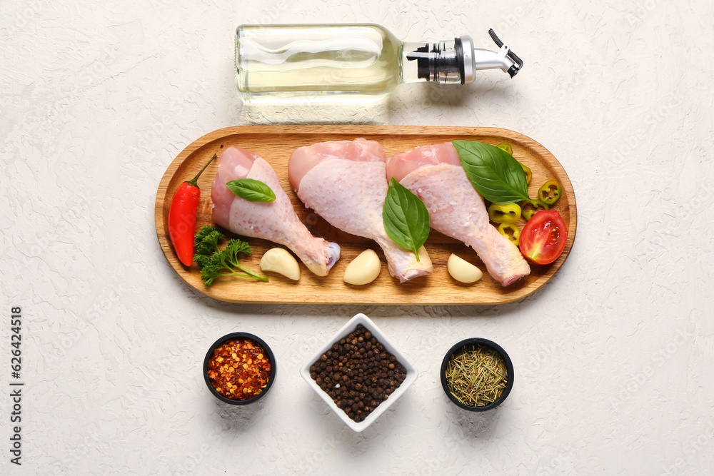 Composition with raw chicken legs, spices and oil on light background