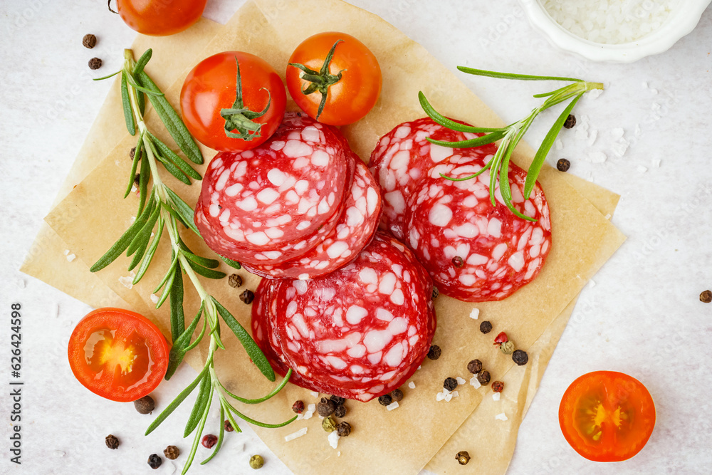 Slices of tasty salami on light background