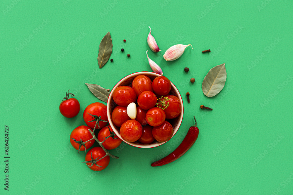 Bowl with canned tomatoes and garlic on green background