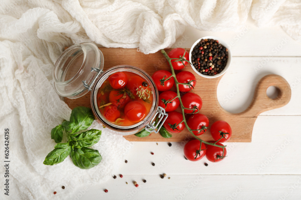 Jar with canned tomatoes and basil on white wooden table