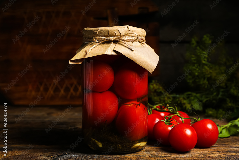 Jar with canned tomatoes on wooden background