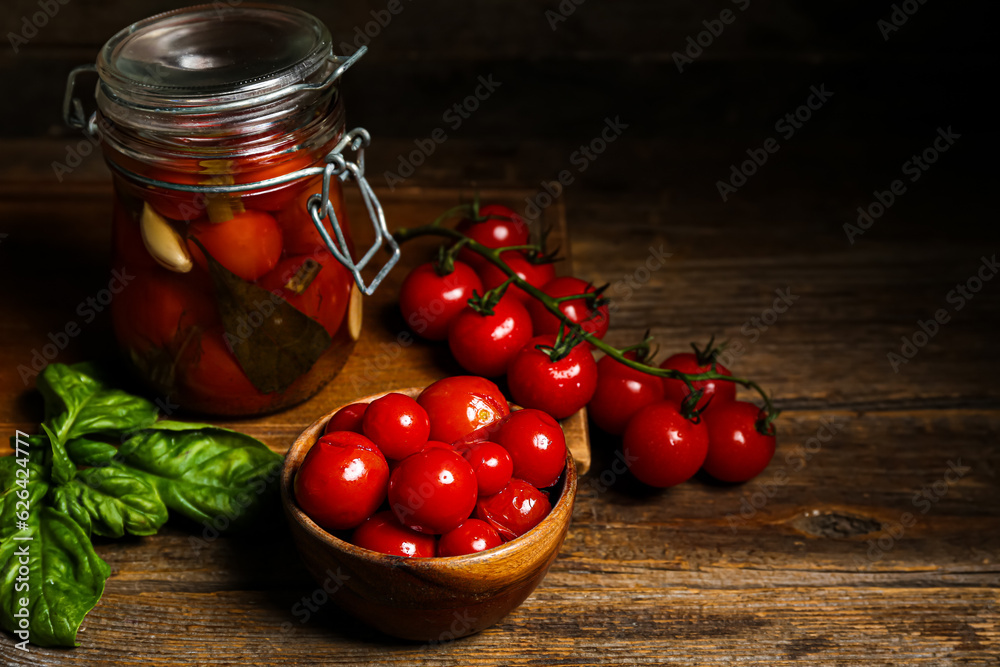 Jar and bowl with canned tomatoes on wooden background